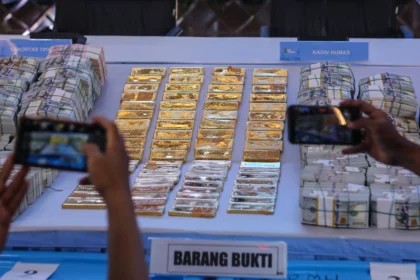 Wartawan memfoto barang bukti emas dan sejumlah uang saat ditampilkan pada konferensi pers di Polda Metro Jaya, Jakarta, Jumat (10/7/2026).