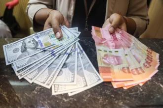 Karyawan menunjukkan uang pecahan rupiah dan dolar Amerika Serikat (AS) di gerai penukaran uang asing Dolarasia Money Changer Cibubur, di Jatisampurna, Bekasi, Jawa Barat, Kamis (9/7/2026).