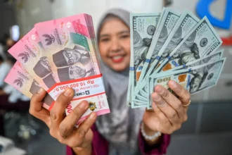 Karyawan menunjukkan uang pecahan rupiah dan dolar Amerika Serikat (AS) di salah satu gerai penukaran mata uang asing di Jakarta, Senin (27/7/2026). (Sumber: Antara Foto/Rivan Awal Lingga/nz)