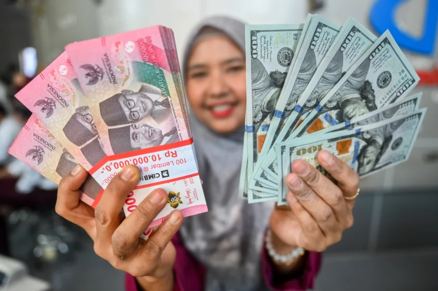 Karyawan menunjukkan uang pecahan rupiah dan dolar Amerika Serikat (AS) di salah satu gerai penukaran mata uang asing di Jakarta, Senin (27/7/2026). (Sumber: Antara Foto/Rivan Awal Lingga/nz)