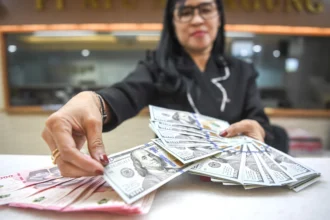 Karyawan menghitung uang pecahan rupiah dan dolar Amerika Serikat (AS) di gerai penukaran mata uang asing Ayu Masagung, Jakarta, Senin (13/7/2026).