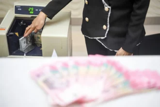 Karyawan menghitung uang pecahan rupiah dan dolar Amerika Serikat (AS) di gerai penukaran mata uang asing Ayu Masagung, Jakarta, Senin (13/7/2026).