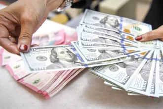 Karyawan menghitung uang pecahan rupiah dan dolar Amerika Serikat (AS) di gerai penukaran mata uang asing Ayu Masagung, Jakarta, Senin (13/7/2026).