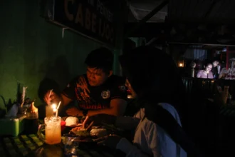 Warga berada di tempat makan dengan penerangan lilin saat terjadi pemadaman listrik bergilir di Palangka Raya, Kalimantan Tengah, Rabu (1/7/2026).