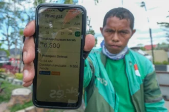 Seorang pengemudi ojek daring (ojol) menunjukkan riwayat pendapatannya di Kendari, Sulawesi Tenggara, Senin (29/6/2026).