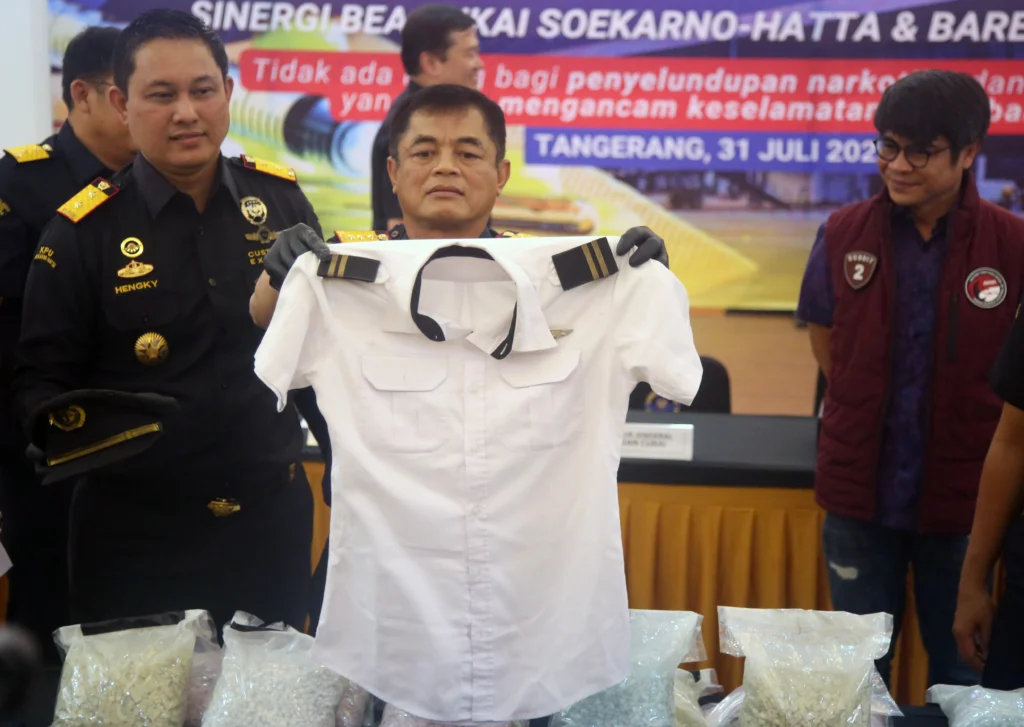 Direktur Jenderal Bea dan Cukai Djaka Budhi Utama (tengah) didampingi Kepala Kantor Bea Cukai Bandara Soekarno-Hatta Hengky Aritonang (kiri) dan Kasubdit 2 Dittipidnarkoba Bareskrim Polri Kombes Pol. Awaludin Amin (kanan) menunjukkan seragam pilot milik tersangka saat konferensi pers pengungkapan penyelundupan ekstasi dan sabu di Kantor Bea Cukai Bandara Soekarno-Hatta, Tangerang, Banten, Jumat (31/7/2026).