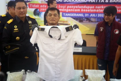 Direktur Jenderal Bea dan Cukai Djaka Budhi Utama (tengah) didampingi Kepala Kantor Bea Cukai Bandara Soekarno-Hatta Hengky Aritonang (kiri) dan Kasubdit 2 Dittipidnarkoba Bareskrim Polri Kombes Pol. Awaludin Amin (kanan) menunjukkan seragam pilot milik tersangka saat konferensi pers pengungkapan penyelundupan ekstasi dan sabu di Kantor Bea Cukai Bandara Soekarno-Hatta, Tangerang, Banten, Jumat (31/7/2026).