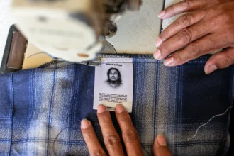 Penjahit menjahit label atau merek profil dirinya ke pakaian jahitannya di rumah produksi Kubik Society, Sangkrah, Pasar Kliwon, Solo, Jawa Tengah. (Sumber: Antara Foto/Mohammad Ayudha/wsj)