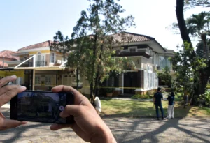 Jurnalis televisi merekam suasana rumah mewah yang dipasangi garis polisi usai penggeledahan di kawasan Sentul, Babakan Madang, Kabupaten Bogor, Jawa Barat, Kamis (9/7/2026).