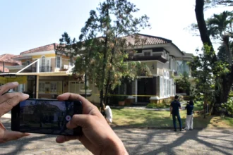 Jurnalis televisi merekam suasana rumah mewah yang dipasangi garis polisi usai penggeledahan di kawasan Sentul, Babakan Madang, Kabupaten Bogor, Jawa Barat, Kamis (9/7/2026).