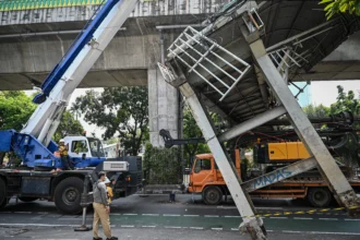 Petugas melakukan proses evakuasi truk bermuatan alat berat yang menabrak jembatan penyeberangan orang (JPO) di Jalan Kapten Tendean, Jakarta, Selasa (14/7/2026).