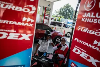 Petugas SPBU melayani pengisian bahan bakar minyak (BBM) kepada pengendara motor.
