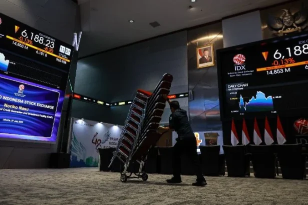Pekerja melintas di dekat layar pergerakan Indeks Harga Saham Gabungan (IHSG) di Bursa Efek Indonesia (BEI), Jakarta.