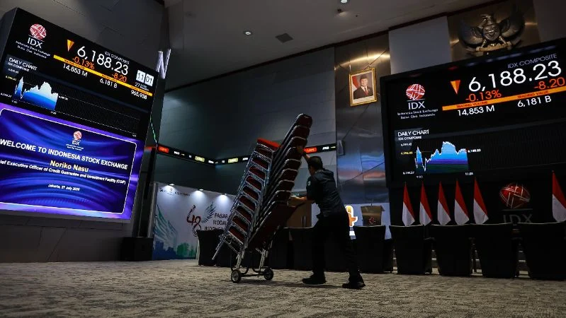 Pekerja melintas di dekat layar pergerakan Indeks Harga Saham Gabungan (IHSG) di Bursa Efek Indonesia (BEI), Jakarta.
