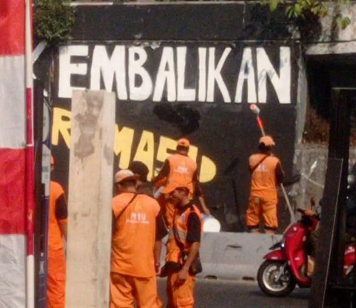 Petugas Dinas Kebersihan Jakarta Barat Menghapus Mural Mahasiswa Trisakti.