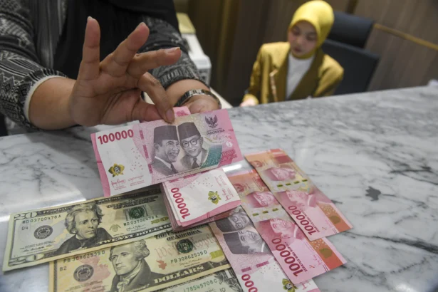 Petugas menunjukkan pecahan mata uang Rupiah dan Dolar AS di Kantor Cabang BNI Pasar Baru, Jakarta, Kamis (20/8/2026).