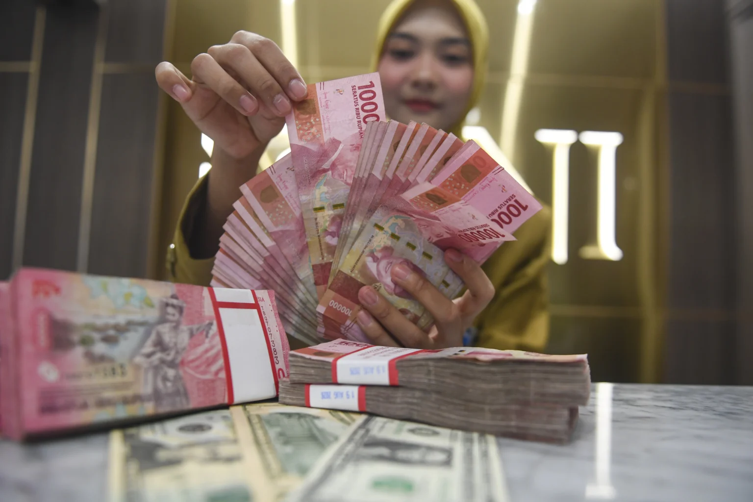 Petugas menunjukkan pecahan mata uang Rupiah dan Dolar AS di Kantor Cabang BNI Pasar Baru, Jakarta. (Sumber: Antara Foto/Muhammad Adimaja/nym)