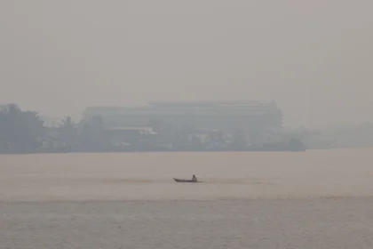 Sebuah perahu melintasi Sungai Kapuas yang diselimuti kabut asap di Pontianak, Kalimantan Barat