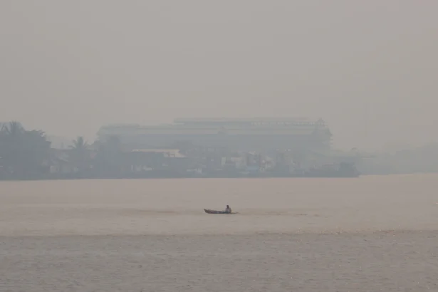 Sebuah perahu melintasi Sungai Kapuas yang diselimuti kabut asap di Pontianak, Kalimantan Barat