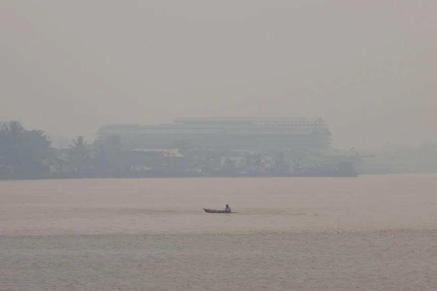 Sebuah perahu melintasi Sungai Kapuas yang diselimuti kabut asap di Pontianak, Kalimantan Barat