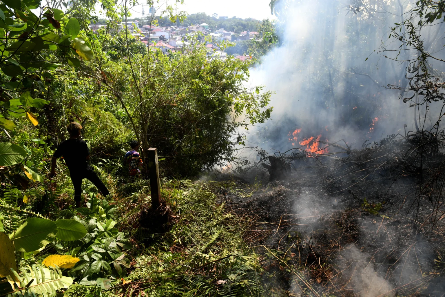 Warga berusaha memadamkam api saat terjadi kebakaran lahan di kawasan Gunung Bahagia, Balikpapan, Kalimantan Timur