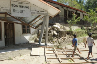 Warga melintas di samping bangunan sekolah yang rusak akibat gempa bumi magnitudo 7,7 di Pulau Palue, Kabupaten Sikka, NTT