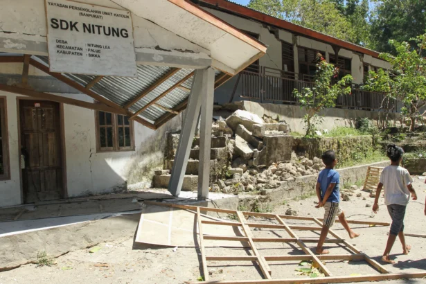 Warga melintas di samping bangunan sekolah yang rusak akibat gempa bumi magnitudo 7,7 di Pulau Palue, Kabupaten Sikka, NTT
