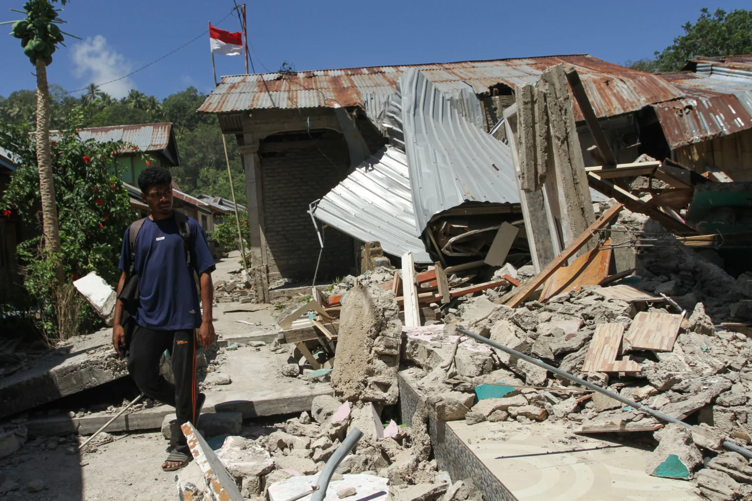 Warga melintas di samping bangunan rumah yang roboh akibat gempa bumi magnitudo 7,7 di Pulau Palue, Kabupaten Sikka, NTT
