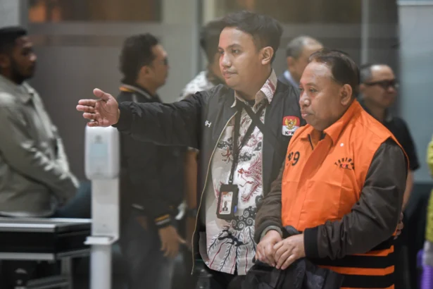 Rektor Universitas Jenderal Soedirman (Unsoed) Akhmad Sodiq (kanan) berjalan menuju mobil tahanan seusai menjalani pemeriksaan di Gedung Merah Putih KPK, Jakarta, Sabtu (22/8/2026) dini hari.