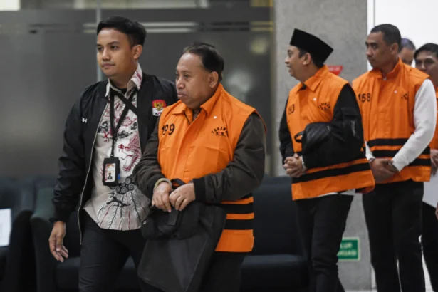 Rektor Universitas Jenderal Soedirman (Unsoed) Akhmad Sodiq (kedua kiri) berjalan menuju mobil tahanan seusai menjalani pemeriksaan di Gedung Merah Putih KPK, Jakarta, Sabtu (22/8/2026) dini hari.