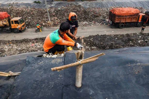 Petugas memasang patok pada geomembran sebagai media pelindung untuk menutup tumpukan sampah di Tempat Pengolahan Sampah Terpadu (TPST) Bantargebang, Kota Bekasi, Jawa Barat