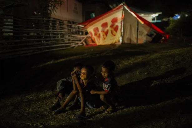 Sejumlah anak bermain gawai di depan tenda pengungsian di Pota, Sambi Rampas, Manggarai Timur, Nusa Tenggara Timur (NTT), Minggu (23/8/2026).
