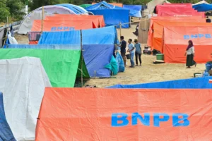 Pengungsi korban gempa bumi Nusa Tenggara Timur (NTT) berjalan di dekat tenda posko pengungsian di Lapangan Barangkolong, Reo, Kabupaten Manggarai, NTT
