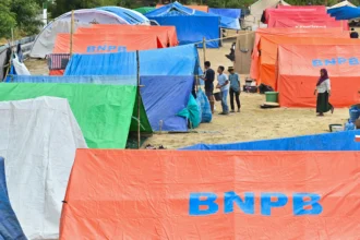 Pengungsi korban gempa bumi Nusa Tenggara Timur (NTT) berjalan di dekat tenda posko pengungsian di Lapangan Barangkolong, Reo, Kabupaten Manggarai, NTT