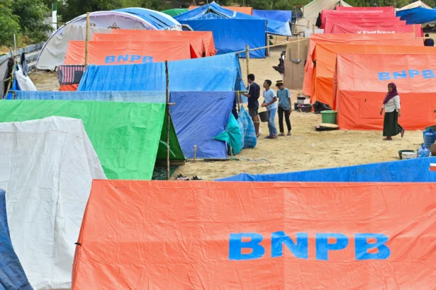 Pengungsi korban gempa bumi Nusa Tenggara Timur (NTT) berjalan di dekat tenda posko pengungsian di Lapangan Barangkolong, Reo, Kabupaten Manggarai, NTT