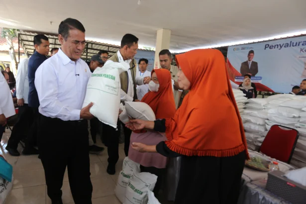 Menteri Pertanian sekaligus Kepala Badan Pangan Nasional (Bapanas) Andi Amran Sulaiman (kiri) didampingi Dirut Perum Bulog Ahmad Rizal Ramdhani (kedua kiri) menyerahkan bantuan pangan beras alokasi bulan Juli, Agustus, dan September kepada warga di Surabaya, Jawa Timur