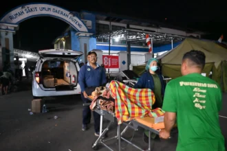 Petugas medis memindahkan pasien ke dalam tenda darurat di RSUD Ruteng, Kabupaten Manggarai, NTT, Minggu (16/8/2026).