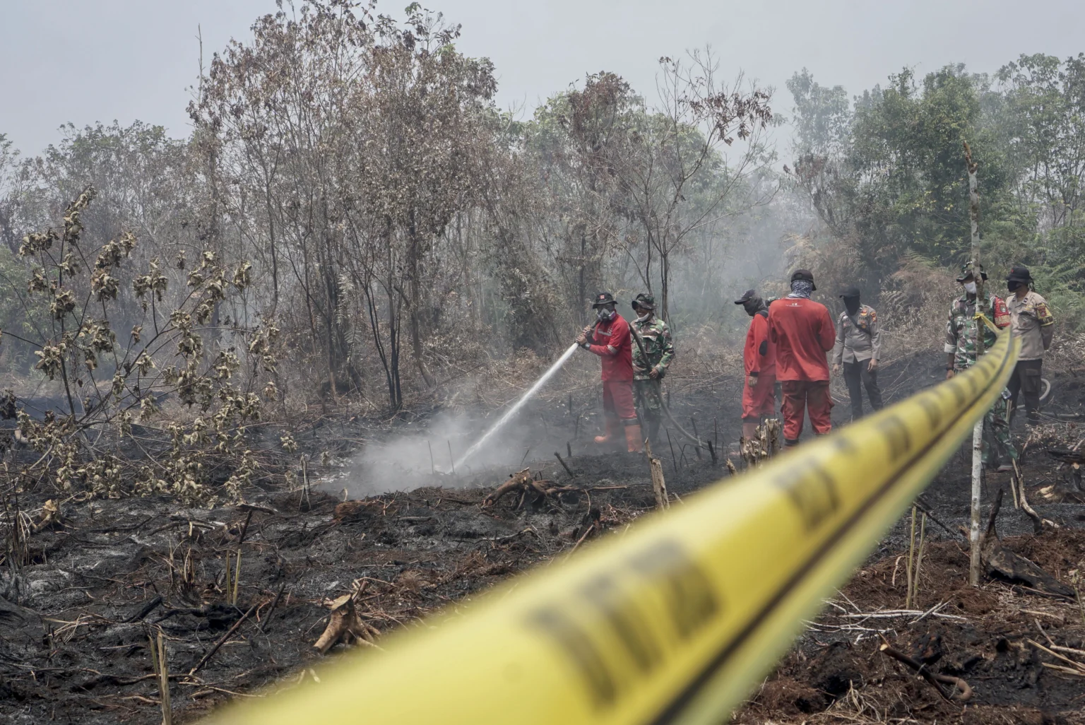 Petugas Kepolisian Polres Kampar dibantu Satgas Karhutla Riau memasang garis polisi saat menyegel lahan seluas lima hektare yang terbakar di Desa Rimbo Panjang, Kabupaten Kampar, Riau, Sabtu (22/8/2026).