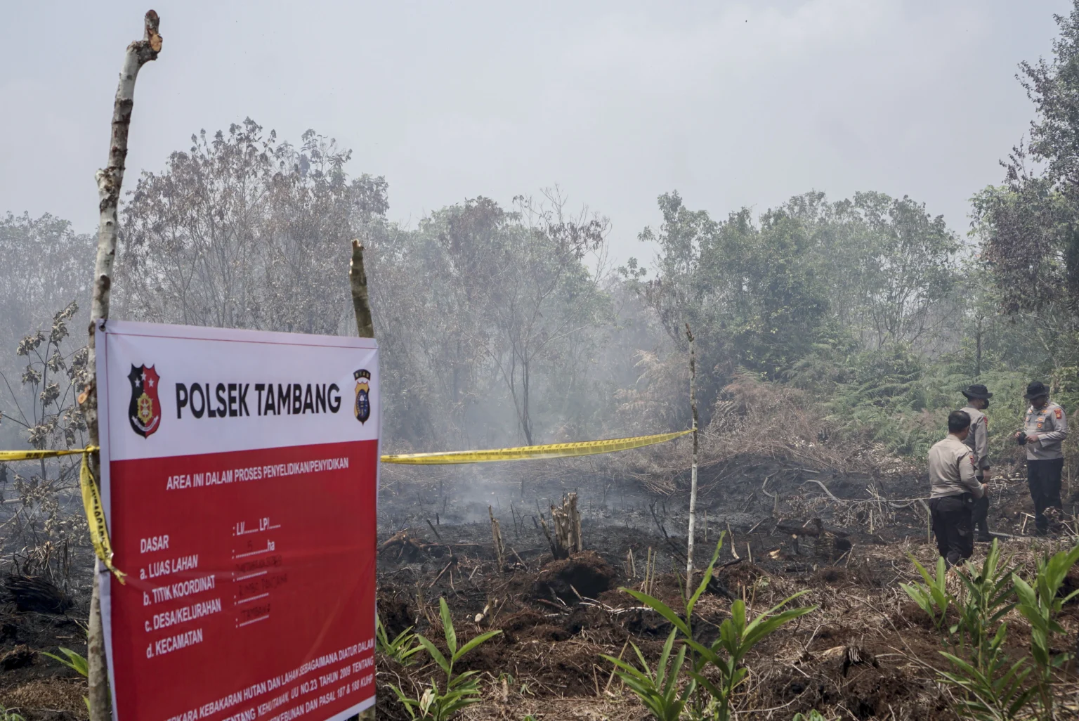 Petugas Kepolisian Polres Kampar memasang garis polisi saat menyegel lahan seluas lima hektare yang terbakar di Desa Rimbo Panjang, Kabupaten Kampar, Riau, Sabtu (22/8/2026).