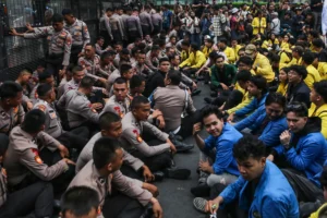 Petugas kepolisian dan mahasiswa duduk bersama saat berlangsung unjuk rasa di Jalan MH Thamrin, Jakarta, Selasa (18/8/2026).