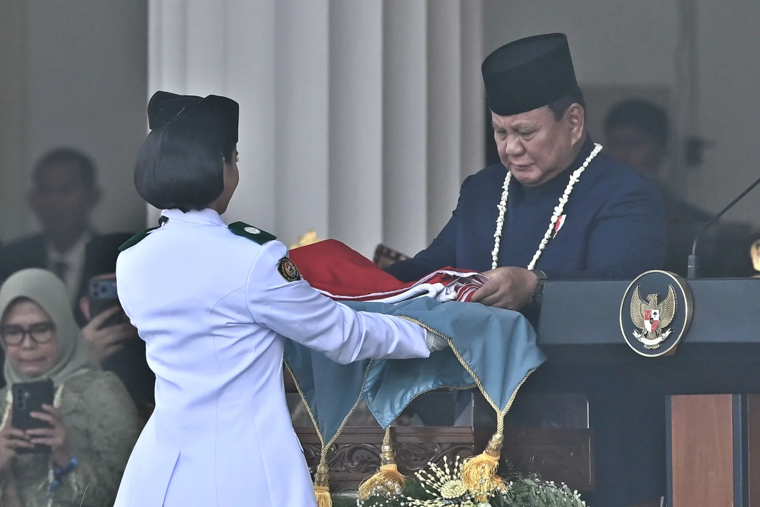 Presiden Prabowo Subianto (kanan) menyerahkan duplikat Bendera Pusaka Merah Putih kepada anggota Pasukan Pengibar Bendera Pusaka (Paskibraka) Celina Olivia Apriani Theo (kiri) pada Upacara Peringatan Detik-Detik Proklamasi Kemerdekaan Ke-81 Republik Indonesia di Istana Merdeka, Jakarta