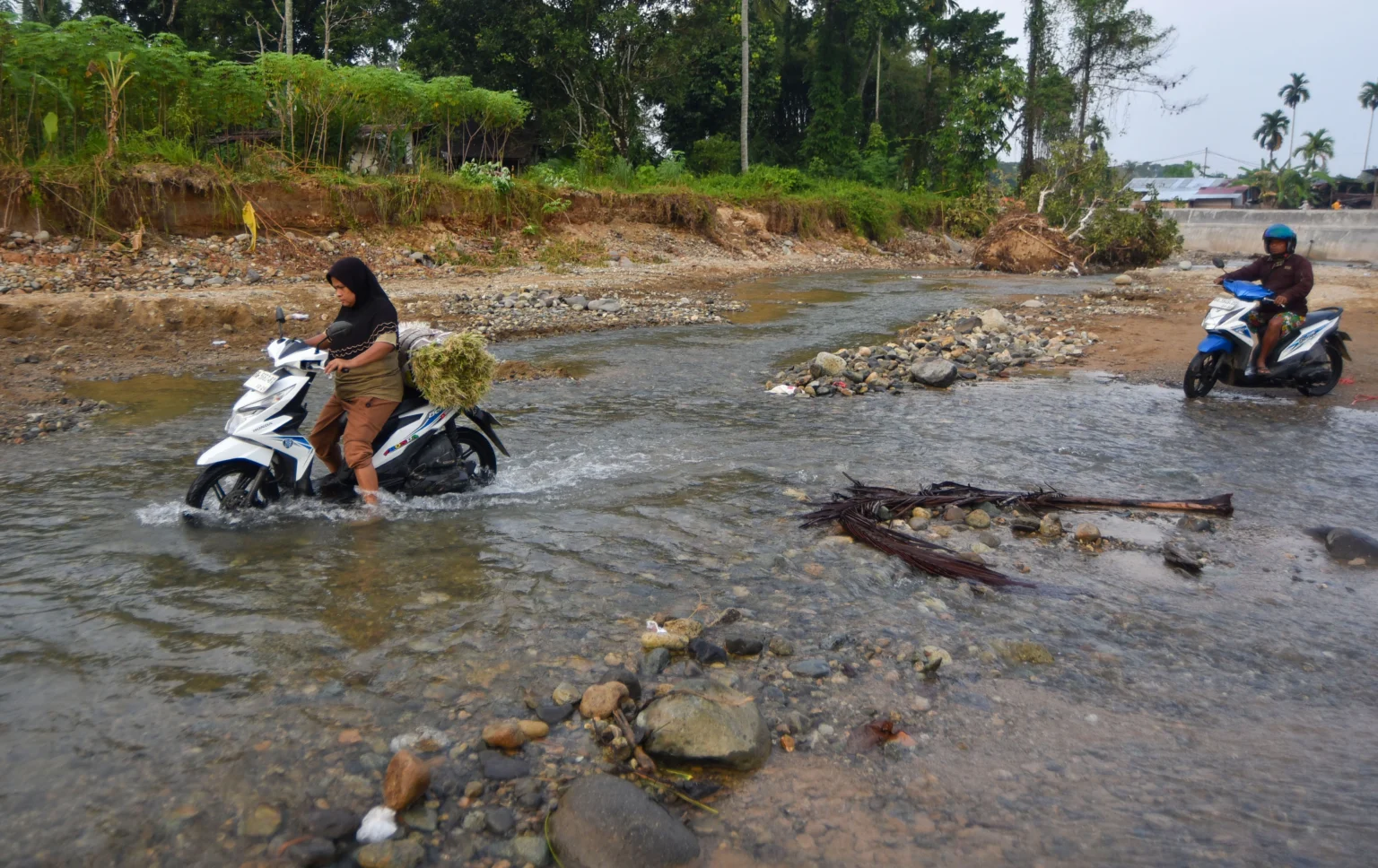 Warga mengendarai sepeda motor menyeberangi Sungai Batang Belimbing di Kampung Tanjung, Kuranji, Padang, Sumatera Barat,