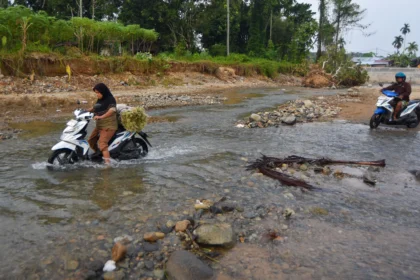 Warga mengendarai sepeda motor menyeberangi Sungai Batang Belimbing di Kampung Tanjung, Kuranji, Padang, Sumatera Barat,