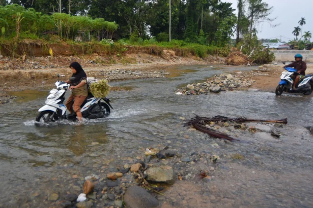 Warga mengendarai sepeda motor menyeberangi Sungai Batang Belimbing di Kampung Tanjung, Kuranji, Padang, Sumatera Barat,
