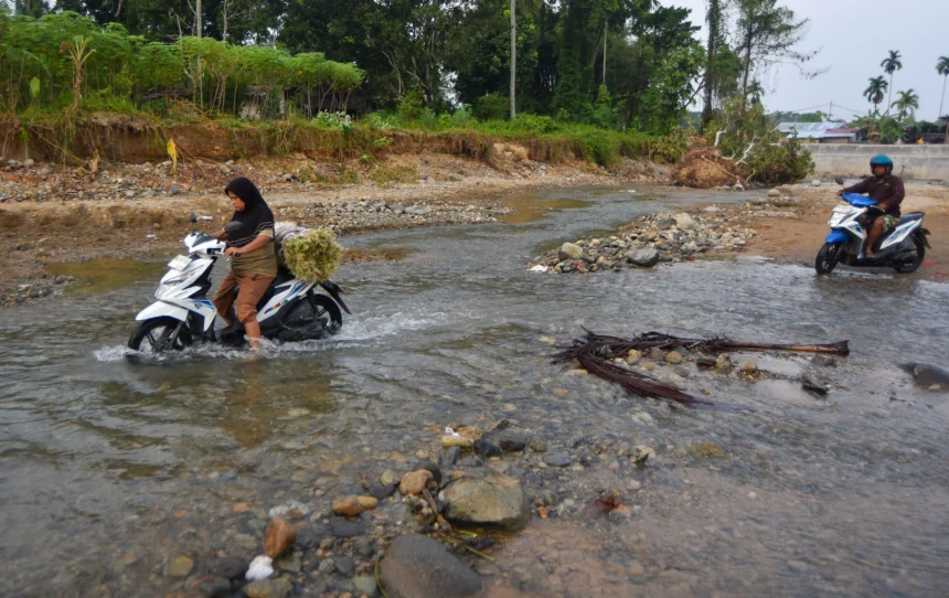 Warga mengendarai sepeda motor menyeberangi Sungai Batang Belimbing di Kampung Tanjung, Kuranji, Padang, Sumatera Barat,