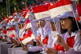 Anak-anak mengibarkan bendera Indonesia