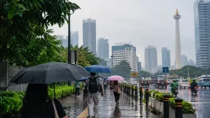 Ilustrasi warga memakai payung saat huja gerimis di Jakarta.
