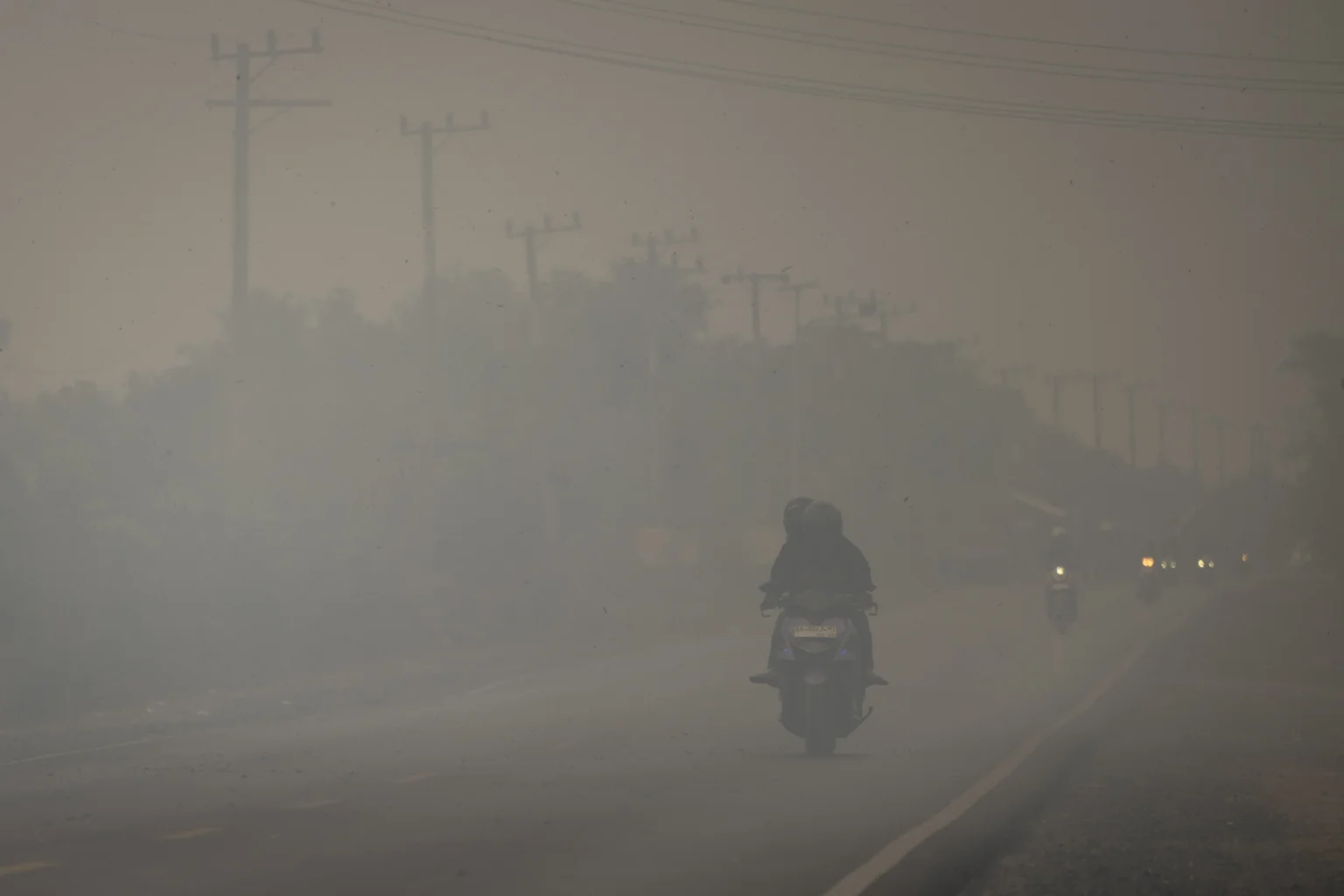 Pengendara sepeda motor melintas di Jalan Gubernur Syarkawi yang tertutup kabut asap akibat kebakaran hutan dan lahan (karhutla) di Kabupaten Banjar, Kalimantan Selatan