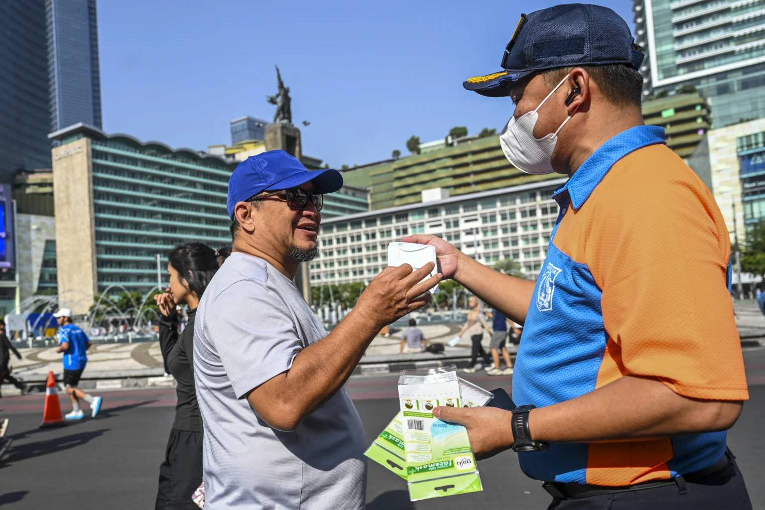 Petugas Dinas Perhubungan DKI Jakarta membagikan masker kepada warga yang berolahraga saat Hari Bebas Kendaraan Bermotor (HBKB) di kawasan Bundaran HI, Jakarta, Minggu (6/9/2026).