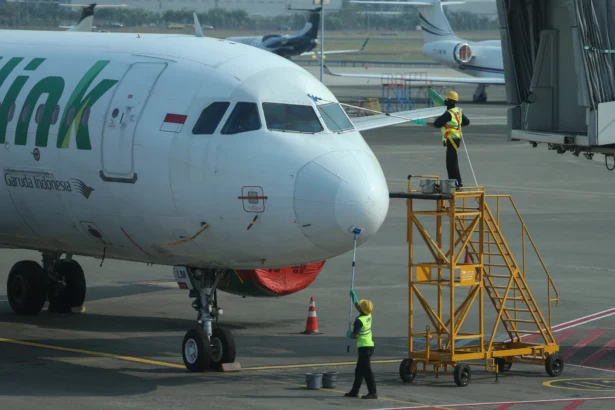 Sejumlah pekerja membersihkan badan pesawat Airbus A320 milik Citilink dari abu vulkanik yang diparkir di apron Terminal 1 Bandara Soekarno-Hatta, Tangerang, Banten